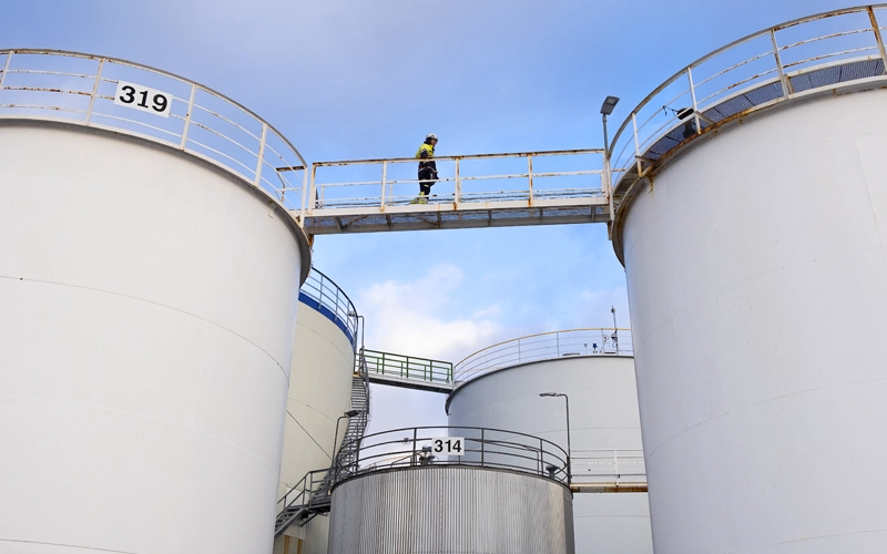 man walking across storage tanks bridge